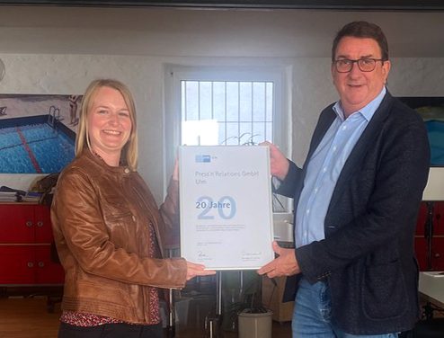 20 Jahre Press'n'Relations" überreicht Lorena Grüner von der IHK Ulm dem Agenturgründer Uwe Pagel eine Urkunde.